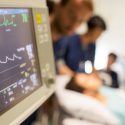 Picture of someone in a hospital bed with medical professionals around them